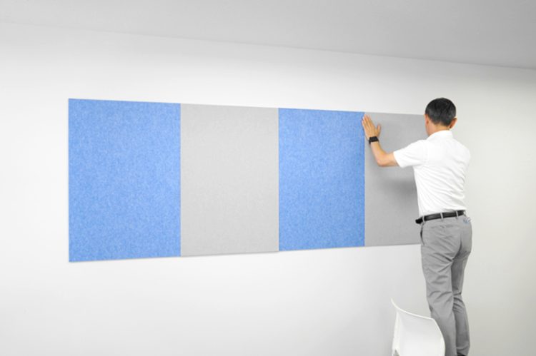 会議室の壁に青とグレーの吸音パネルを交互に貼り終えたところ